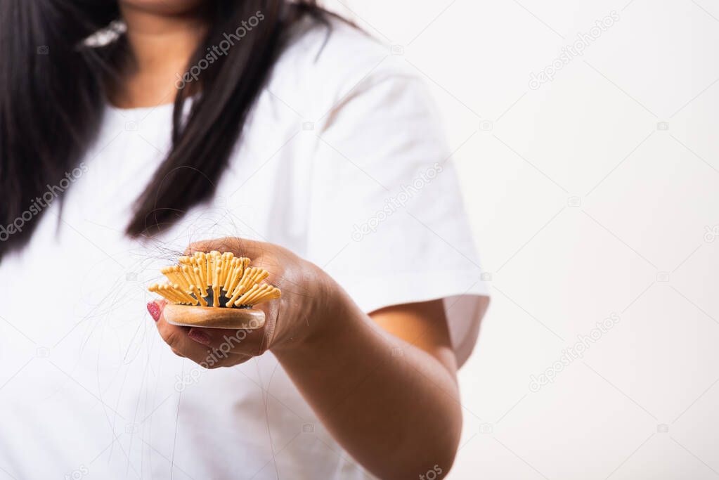 Asian woman unhappy weak hair she shows hairbrush with damaged long loss hair in the comb brush on hand, studio shot isolated on white background, medicine health care concept