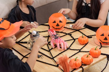 Çocuklar Cadılar Bayramı kutlamalarının tadını çıkarıyorlar. Kabak, örümcek ve örümceklerle örümceklerle dolu, örümcek ağı tasarımı ve boru temizleyici detaylarıyla kaplı sahte bir el hazırlıyorlar..