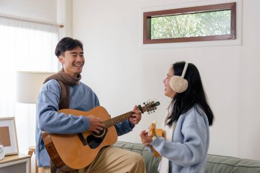 Kış günü kapalı, mutlu çift, aile fertleri rahat ev hayatını, kışın kaynaşmayı, erkek gitar çalmayı, kadın ukulele çalmayı, kalın giysiler giymeyi, neşeyi paylaşmayı sever..