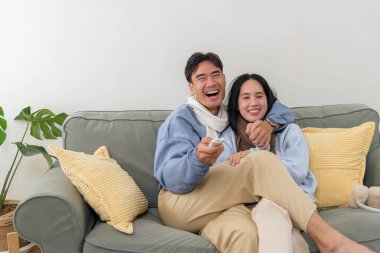 Kış günü evdeki mutlu çifte neşe getiriyor, insanlar evlerinde rahat bir şekilde kanepede dinleniyor, televizyon izlerken sarılıyor ve gülüyor, sıcak anları evlerinde sıcak kış mevsiminde paylaşıyorlar..