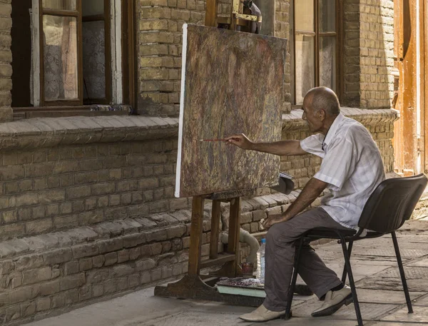 Buhara, Özbekistan - Jule 02, 2018: Yaşlı bir adam bir soyutlama bir boya fırçası ile çizer.