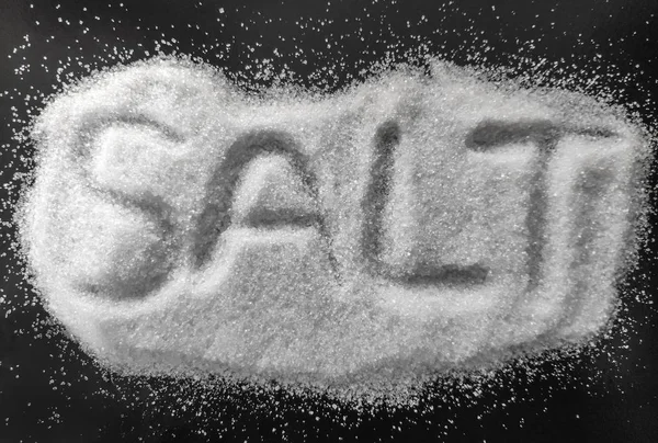 盐概念相片 白色盐查出在黑色背景 天然盐烹饪和水疗的目的与字母上 独立的特写镜头视图 — 图库照片