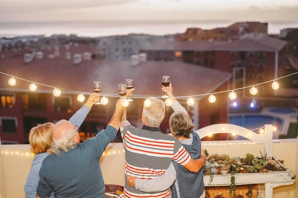 幸せの年長の友人応援と屋上のテラス 年金受給者 退職の概念でバーベキュー パーティーで飲んでと楽しい人々 と成熟の赤ワインで乾杯 — ストック写真