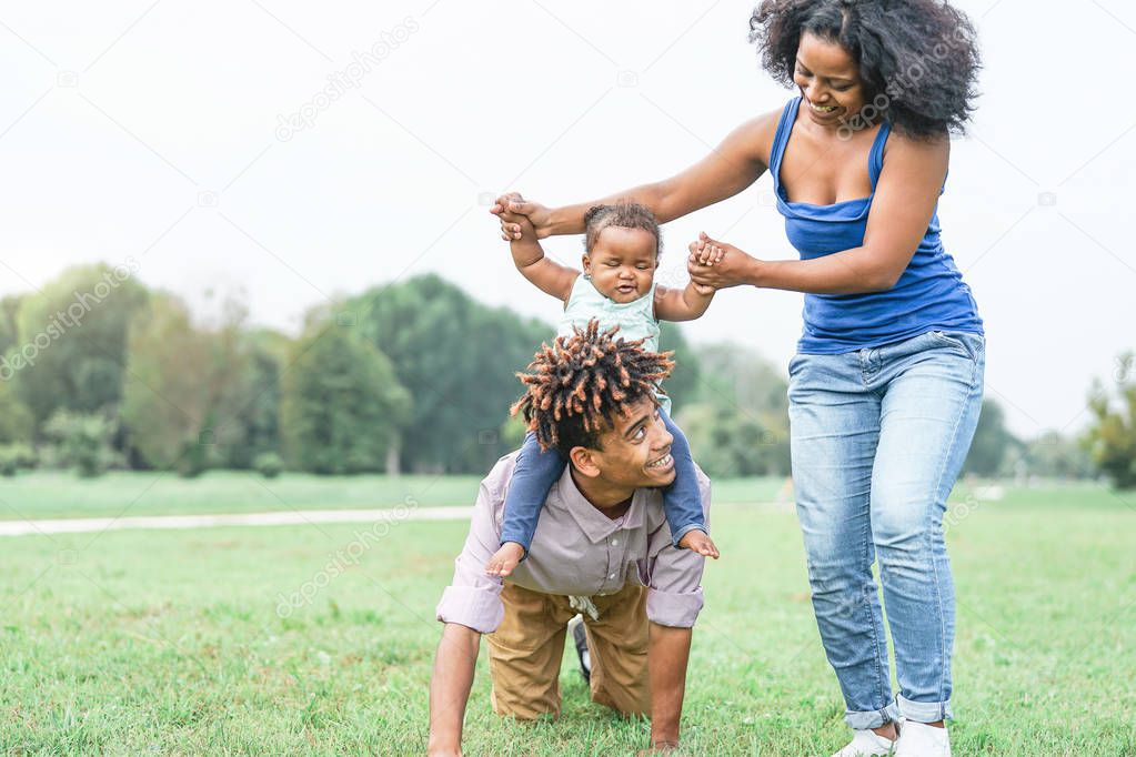 Happy african family having fun in a public park outdoor - Mother and father playing with their daughter during a weekend sunny day - Love and concept happiness