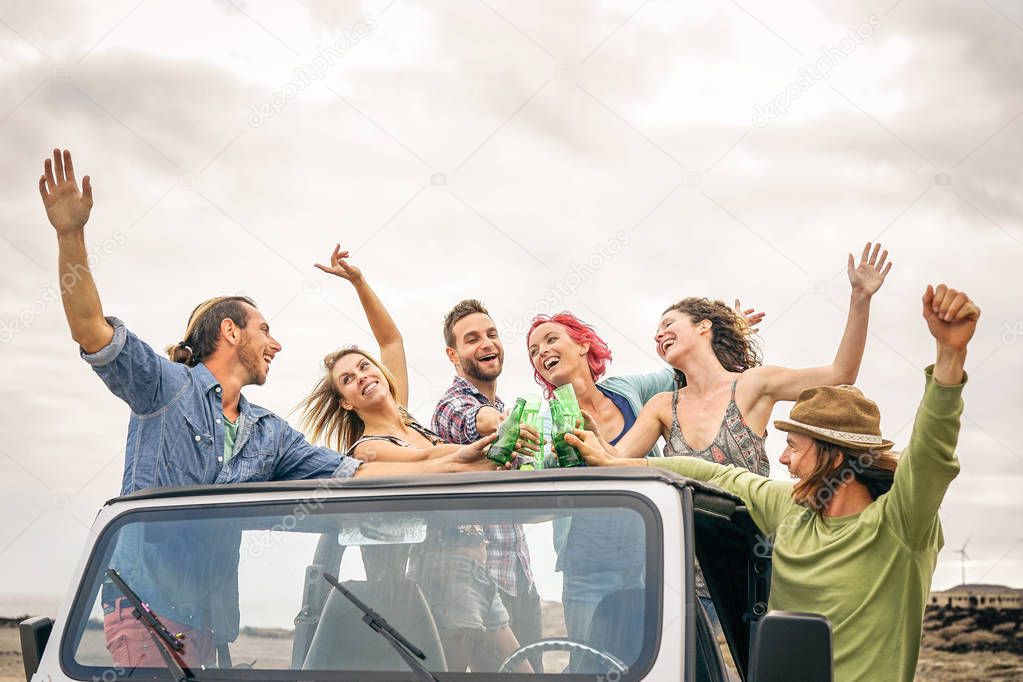 Group of happy friends cheering with beer in convertible car - Young people having fun drinking and making party during their road trip - Friendship, vacation, youth holidays lifestyle concept