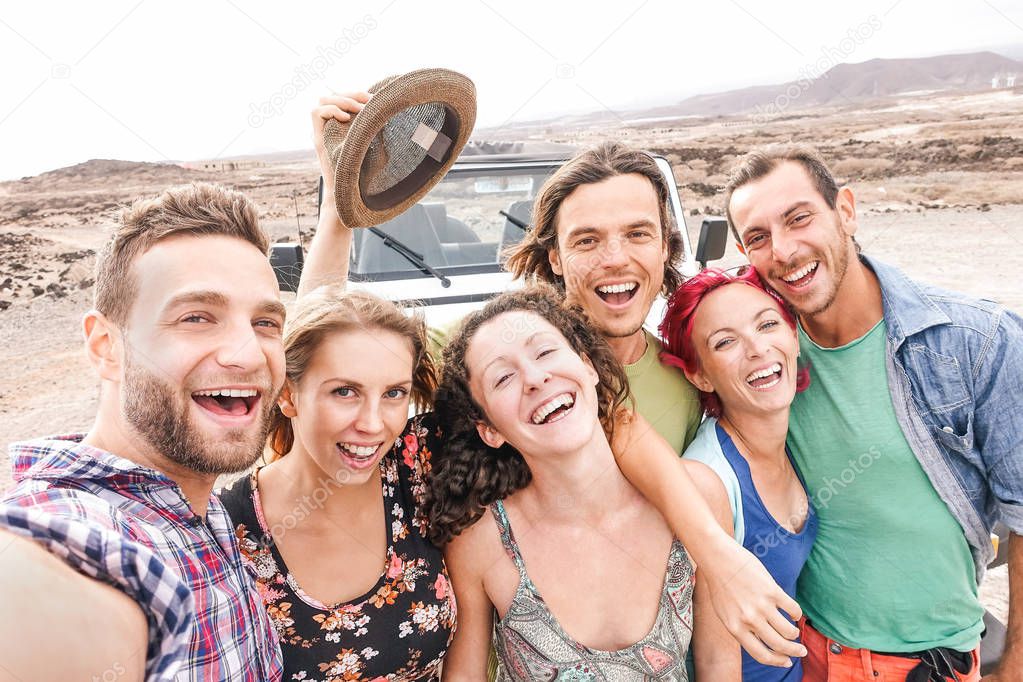 Group of travel friends taking selfie in the desert during a roadtrip - Happy young people having fun traveling together - Friendship, vacation, youth holidays lifestyle concept