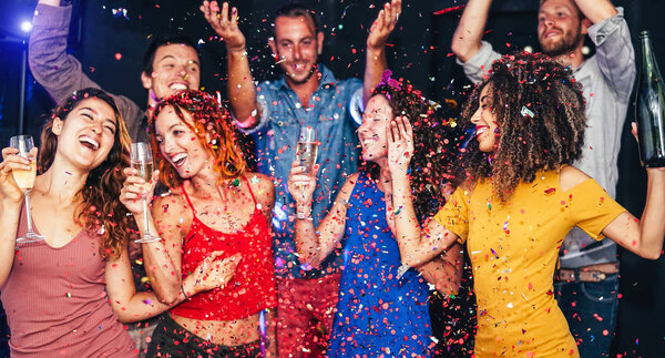 Happy friends doing party dancing and drinking champagne at nightclub - Millennial young people having fun celebrating together and throwing confetti - Entertainment, youth lifestyle holidays concept