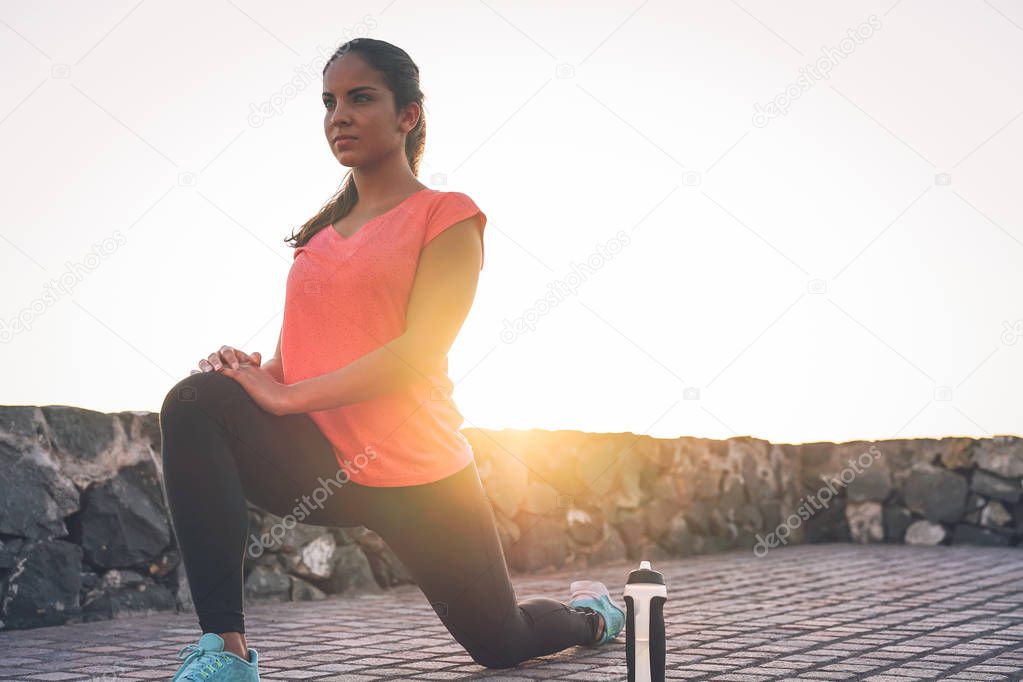 Young attractive woman stretching next the beach during a magnificent sunset - Sporty health girl workout outdoor - Sport, wellness and healthy lifestyle concept