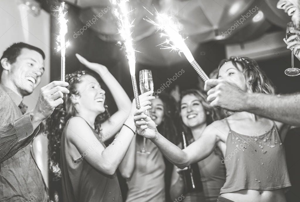 Happy friends doing party dancing and drinking champagne at nightclub - Millennial young people having fun with sparklers fireworks in discoclub - Entertainment, youth lifestyle holidays concept