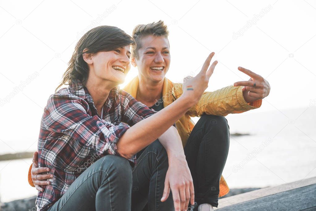 Happy gay couple dating on the beach at sunset - Young lesbians having fun enjoying time together outdoor - Lgbt, homosexuality love and relationship lifestyle concept