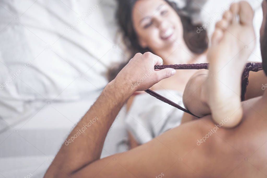 Boyfriend putting off his girlfriend's panties before having sex on bed - Passionate couple having sexy and intimate moments in the bedroom - People relationship, romance love and sexual concept