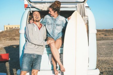 Mutlu sörfçü çift vintage camper mini van - arkasında duran bir minivan ile yolculuğa serüven dolu genç insanların ulaşım - seyahat, tatil, ilişki ve gençlik yaşam tarzı kavramı