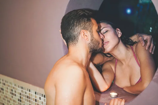 Young romantic couple kissing during a swimming pool spa center day - Passionate lovers having a tender moment on vacation in resort wellness hotel - Concept of people relationship, relax and love