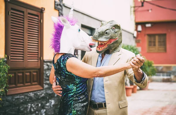 Dans ve dinozor t-rex ve tek boynuzlu at maskesi - karnaval geçit töreninde maskeli eğleniyor üst düzey zarif insanlar - saçma, eksantrik, gerçeküstü, fest ve komik maskeli balo kavramı giyen çılgın çift