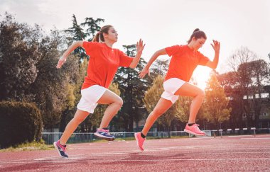 Atletik kızlar genç kadın günbatımı açık - insanlar, sağlıklı, fitness ve spor yaşam tarzı kavramı pistte oturum egzersiz yaparken rekabet - koşma