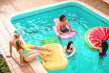 Grup arkadaşıyla mutlu rahatlatıcı yüzme havuzunda - gençler eğleniyor yaz tatil tropikal - dostluk, tatil ve gençlik yaşam tarzı kavramı sırasında hava lilo üzerinde yüzen