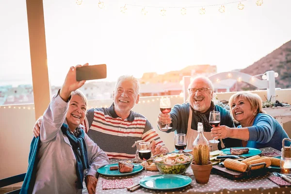 Barbekü akşam yemeği - yetişkin insanlar yeni eğilimleri teknoloji telefon apps kullanırken verandada kırmızı şarap içme ve yemek yeme eğleniyor, hareket eden smartphone kamerayla selfie alarak mutlu büyükler arkadaş
