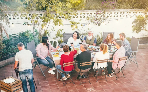 Mutlu aile yemeği ve akşam yemeğinde kırmızı şarap içmek dışarıda barbekü yapmak farklı yaşlarda insanlar bbq partisinde birlikte yemek yemek yemek ebeveynler ve hafta sonu aktiviteleri.