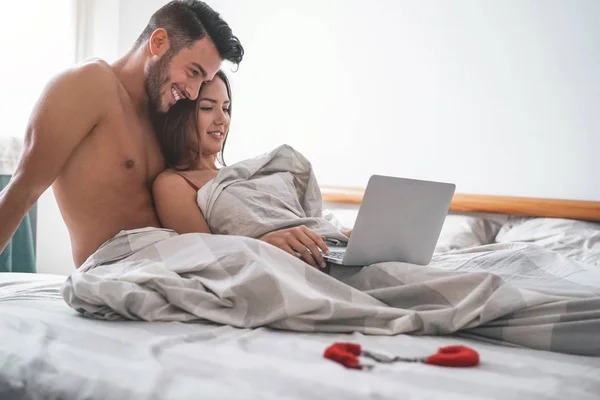 Casal Feliz Assistindo Computador Enquanto Deitado Cama Sob Cobertor Jovem — Fotografia de Stock