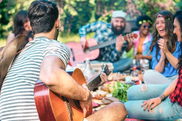 Anak muda yang melakukan piknik dan bermain gitar di taman - Kelompok teman yang bahagia bersenang-senang selama akhir pekan di luar - Persahabatan, makanan dan minuman, kegiatan lucu dan konsep gaya hidup anak muda — Stok Foto