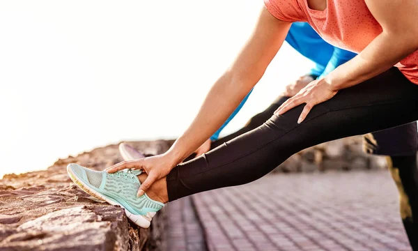 Ajuste par de piernas de estiramiento y entrenamiento al aire libre - Los jóvenes deportivos haciendo ejercicios de sesión de entrenamiento junto a la playa - Deporte, fitness y estilo de vida saludable concepto —  Fotos de Stock