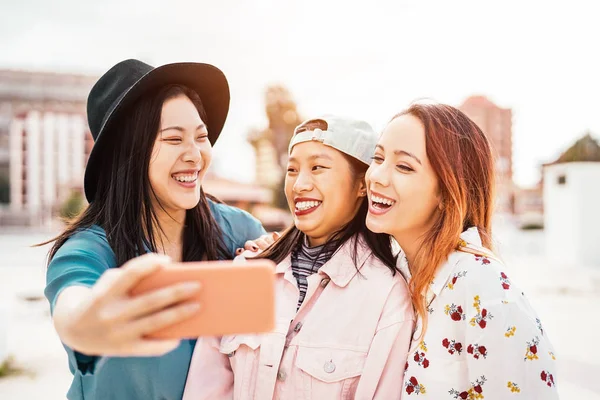 Chicas asiáticas felices tomando selfie con teléfono inteligente móvil al aire libre - Joven adolescente de moda divirtiéndose con la aplicación de nueva tecnología - Personas, social, amistad, tecnología y concepto de estilo de vida juvenil —  Fotos de Stock