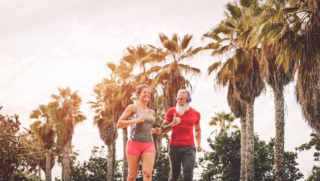 Happy fitness friends running at sunset outdoor - Couple of joggers training at evening time - People jogging, healthy, fit and sport lifestyle concept