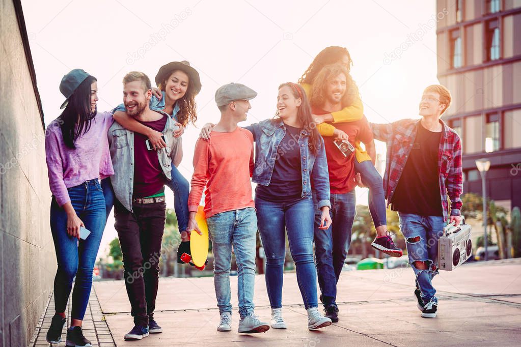 Group of happy friends having fun outdoor - Young people piggybacking while laughing and walking together in the city center - Friendship, millennial generation, teenager and youth lifestyle concept