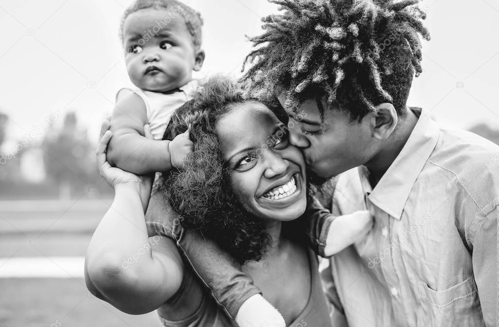 Happy African family having fun in a park outdoor - Mother and father with their daughter enjoying time together in a weekend day - Love and happiness concept - Black and white edit