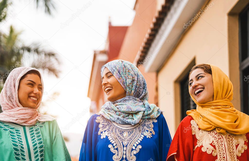 Happy Muslim women walking in the city center - Arabian young girls having fun spending time and laughing together outdoor - concept of people, culture and religion