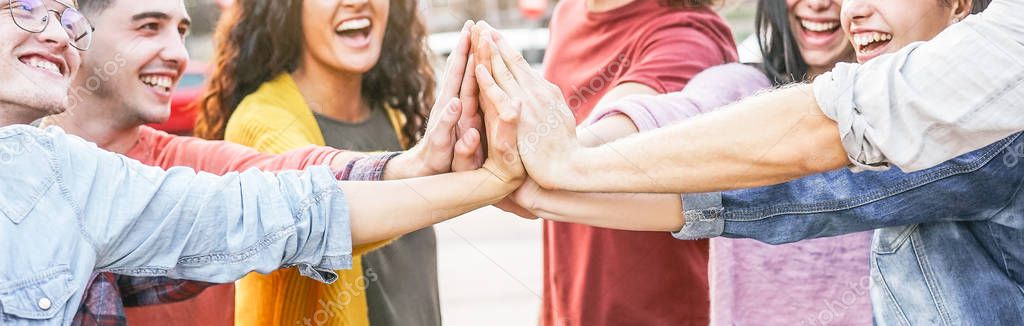 Group of diverse friends stacking hands outdoor - Happy young people having fun joining and celebrating together - Millennials, friendship, empowering, partnership and youth lifestyle concept