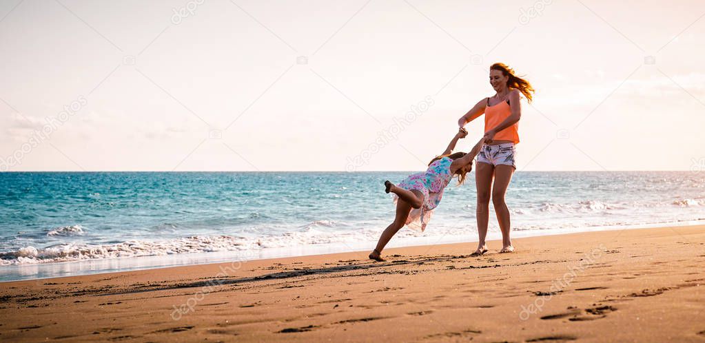 Happy mother and daughter having fun on tropical beach at sunset - Family playing next sea during summer vacation - Concept of parent, love and happiness