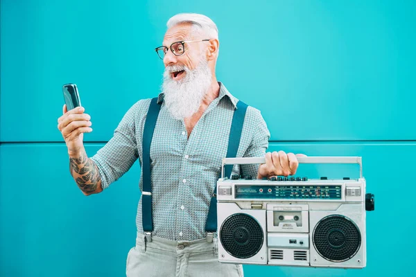 Happy vanhempi mies käyttää matkapuhelinta pitäen vintage boombox ulkona - Muoti hipster uros hauskaa kuunnella musiikkia ja käyttää älypuhelinta ulkona - Teknologia ja vanhusten elämäntapa käsite — kuvapankkivalokuva