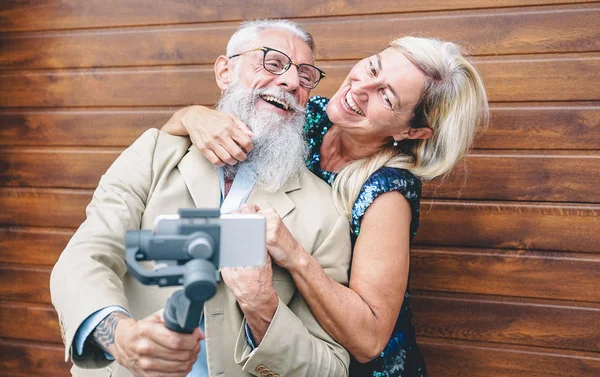 Boldog idősek pár videofelvétel a gimbal mobiltelefon kültéri-érett divat emberek szórakozik az új trendek Smartphone Apps-fa háttér-idős életmód és a technológia fogalma — Stock Fotó