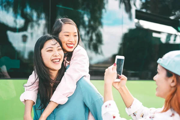 Millennial chicas asiáticas usando el teléfono móvil al aire libre - Jóvenes felices divirtiéndose con la nueva tecnología de aplicaciones para teléfonos inteligentes fuera - Concepto de amistad, tecnología y estilo de vida juvenil adolescente — Foto de Stock