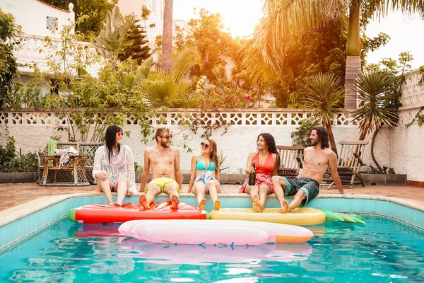 Group of happy friends relaxing in swimming pool - Young people having fun in exclusive summer tropical vacation - Friendship, holidays and youth lifestyle concept — Stock Photo, Image