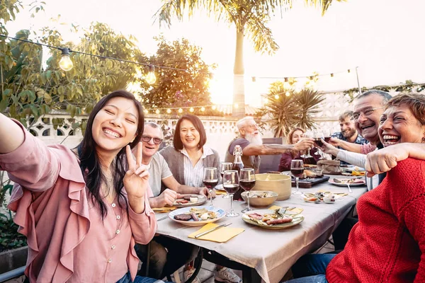 夕食の屋外で赤ワイングラスで幸せな家族の応援と乾杯 - バーベキューパーティーで楽しむ異なる年齢と民族を持つ人々 - 食べ物や飲み物、引退し、若者の概念 — ストック写真