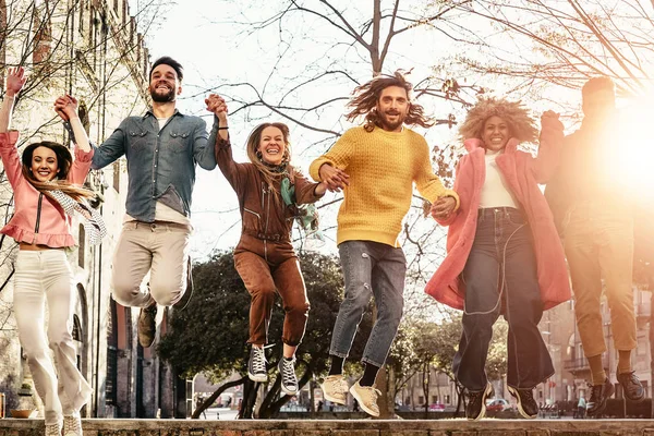 Grupo de amigos felices saltando al aire libre - Jóvenes milenarios divirtiéndose bailando y celebrando al atardecer afuera - Amistad, vida urbana y concepto de estilo de vida juvenil —  Fotos de Stock