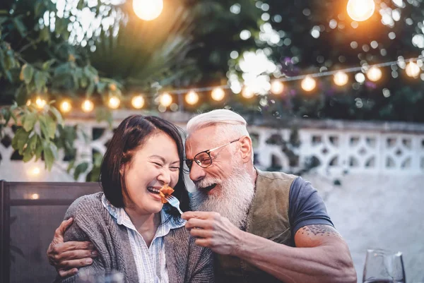 Glückliches Senioren-Paar hat Spaß bei Dinner House Party - Ältere Menschen unterschiedlicher ethnischer Zugehörigkeit machen ein romantisches Date zum Jubiläum - Senioren, Essen, Trinken und Liebeskonzept — Stockfoto