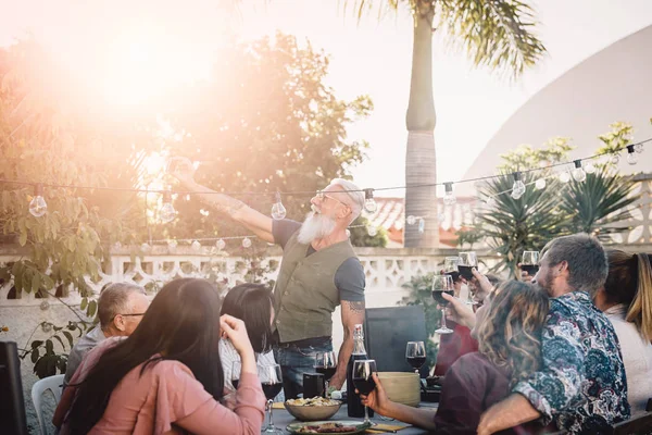 Szczęśliwa rodzina biorąc selfie z aparatem na telefon komórkowy na obiad party na zewnątrz-ludzie z różnym wieku i etnicznego jedzenia razem na patio-jedzenie i picie, emerytów i młodych ludzi koncepcji — Zdjęcie stockowe