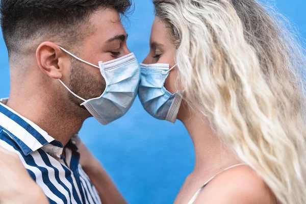 若いですカップルキスしながら顔の外科マスクを身に着けている間コロナウイルス発生中 男と女とともにFacemaskはロマンチックな瞬間を持っています 人々は関係とコロナウイルス防止の概念を愛し — ストック写真