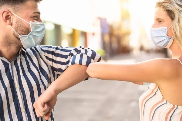 Yüz cerrahisi maskesi takan genç arkadaşlar, Corona virüsü salgınını önlemek için dirsekle yeni bir sosyal mesafe selamlaması yapıyorlar. Fiziksel mesafe ve güvenlik selamlama kavramı.