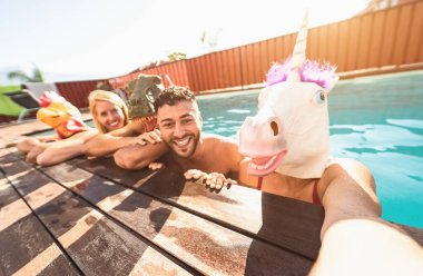 Çılgın arkadaşlar, tuhaf bir maske takarak havuz partisi yapıyorlar, gençler özel bir tropikal tatil köyünde yazı kutlarken eğleniyorlar, arkadaşlık ve gençlerin tatil yaşam tarzı kavramı.