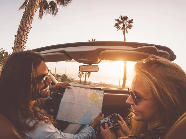 Happy young couple doing road trip in tropical city - Travel people having fun driving in trendy convertible car discovering new places - Relationship and youth vacation lifestyle concept