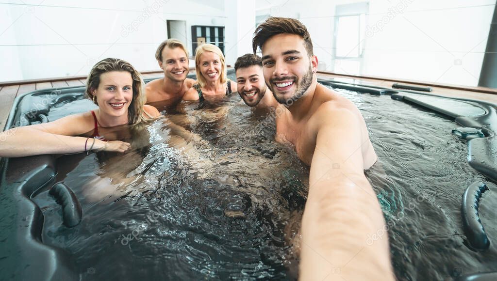 Happy friends taking selfie while doing jacuzzi in luxury house - Young people having fun together in hot tub - Youth millennial generation and wellness lifestyle holidays