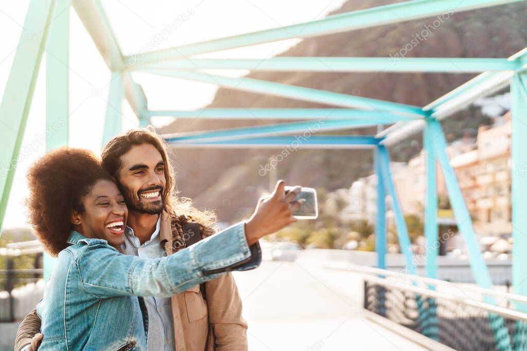Happy smiling couple taking selfie with mobile smartphone outdoor - Young trendy people having fun during vacations - Social people technology addicted and travel trend lifestyle concept