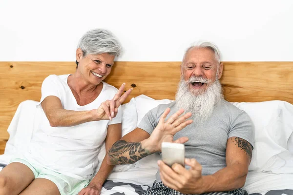 Szczęśliwy Senior Para Wideo Rozmowy Telefonów Komórkowych Poniżej Koce Łóżku — Zdjęcie stockowe