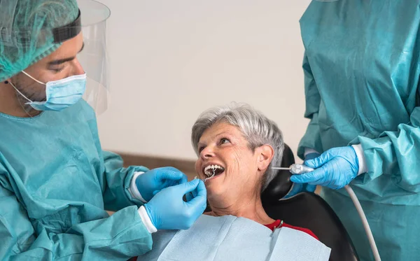 Mężczyzna Dentysta Operujący Starszą Kobietę Klinice Stomatologicznej Koncepcja Pomocy Stomatologicznej — Zdjęcie stockowe