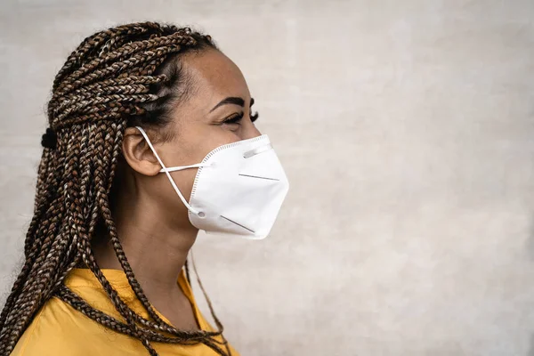 African woman with braids wearing face medical mask - Young girl using facemask for preventing and stop corona virus spread - Healthcare medical and youth millennial people concept