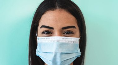 Yüz cerrahisi maskesi takan genç bir kadın Corona virüsünün yayılmasını önlemek ve durdurmak için maske takıyor.